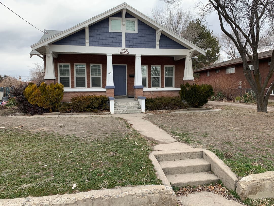 Classic bungalow with blue and brick exterior, front steps, and landscaped yard.