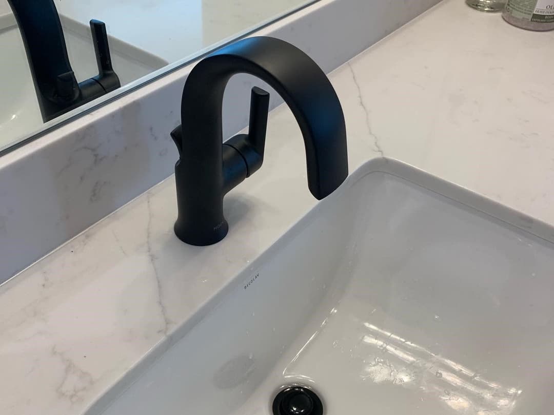 Modern black faucet on a white marble countertop with a sleek sink design.