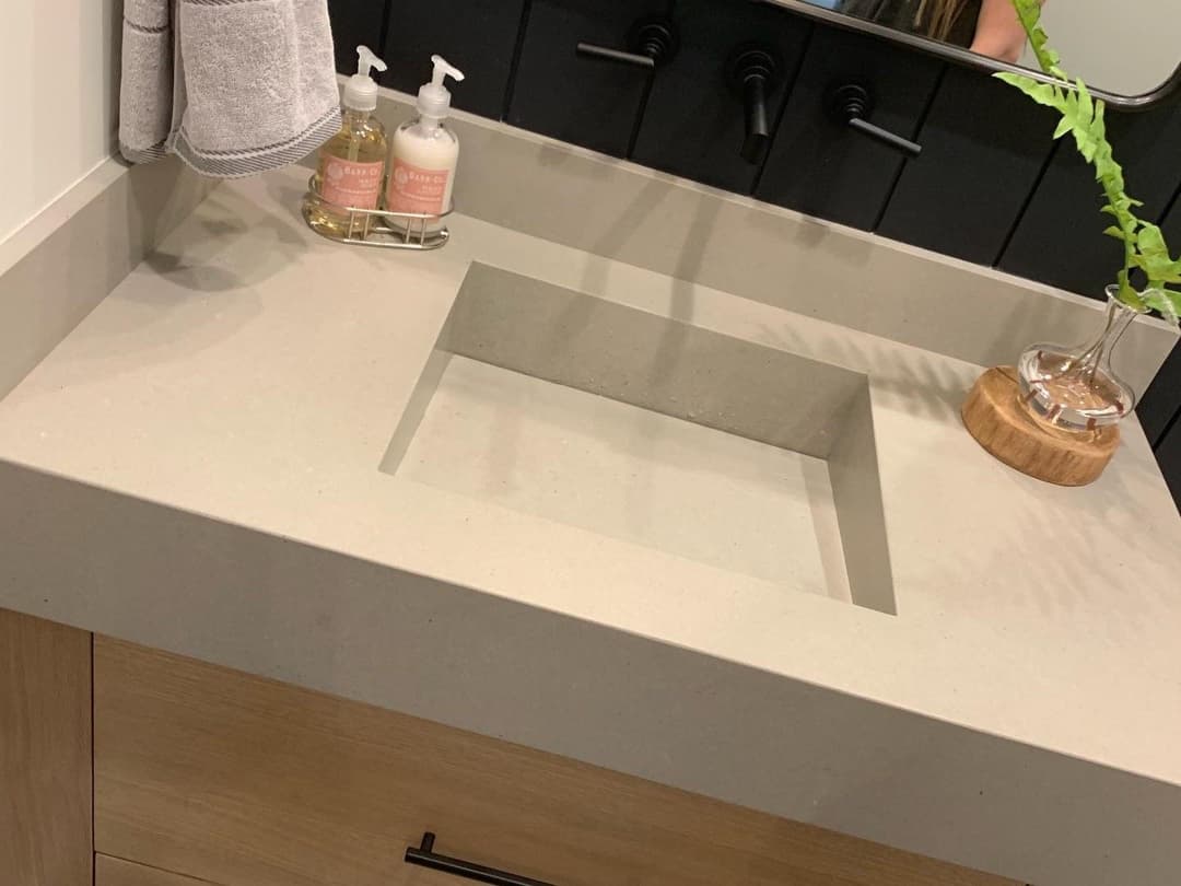 Modern bathroom sink with a square cutout, black faucets, and decorative soap dispensers.
