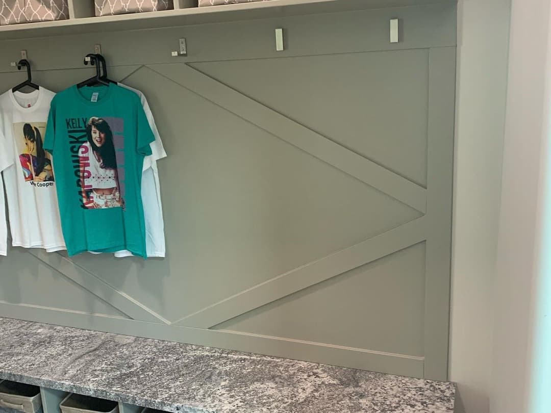 Mudroom with stylish gray wall, hanging shirts, and granite countertop. Organized and modern design.