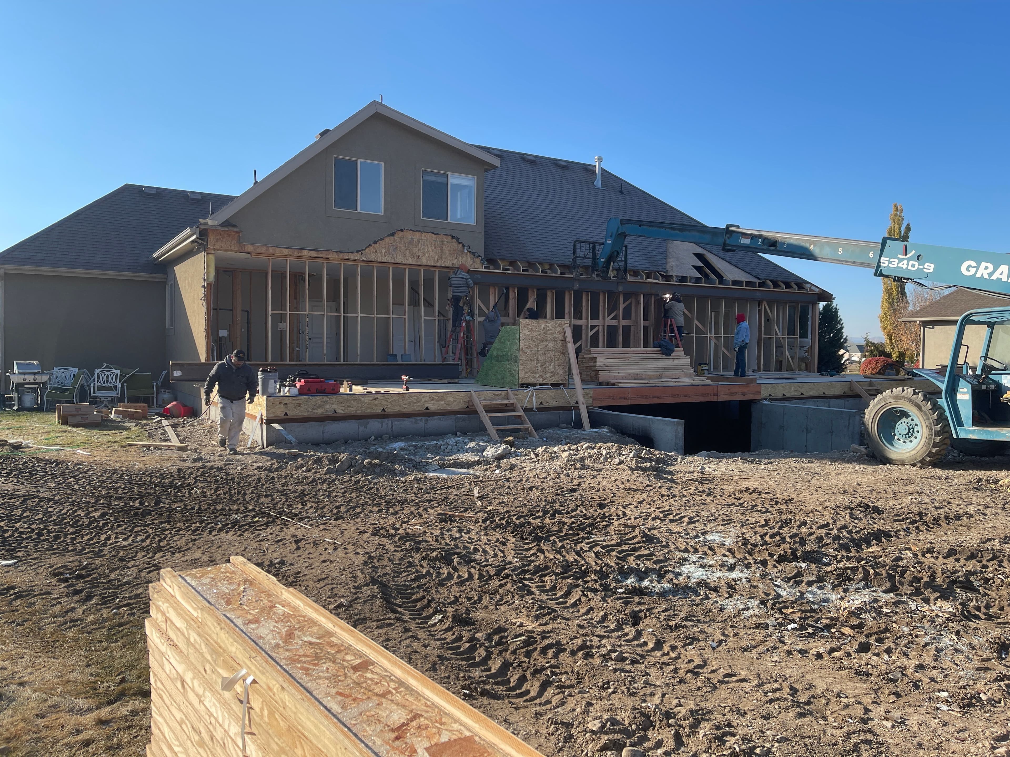 Home renovation in progress with construction workers and equipment at a residential site.