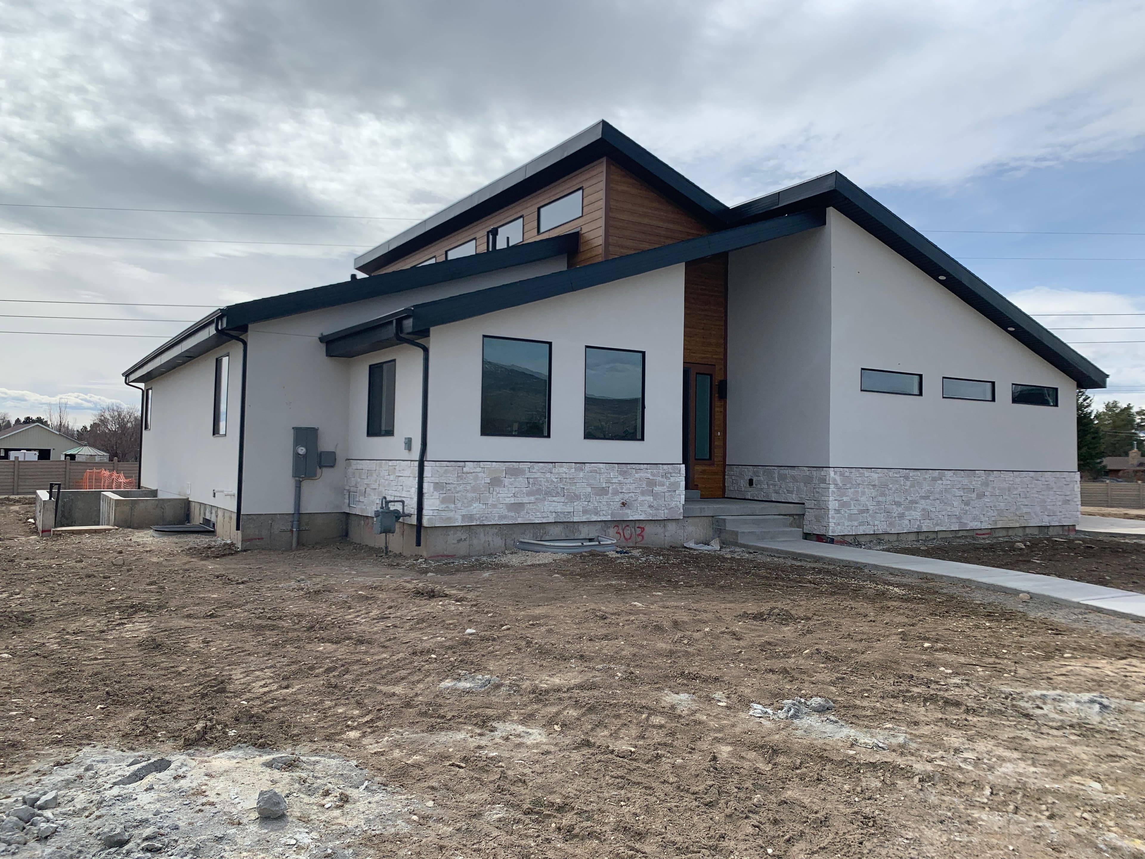 Modern two-story home with stone accents and large windows, set on a cleared lot.