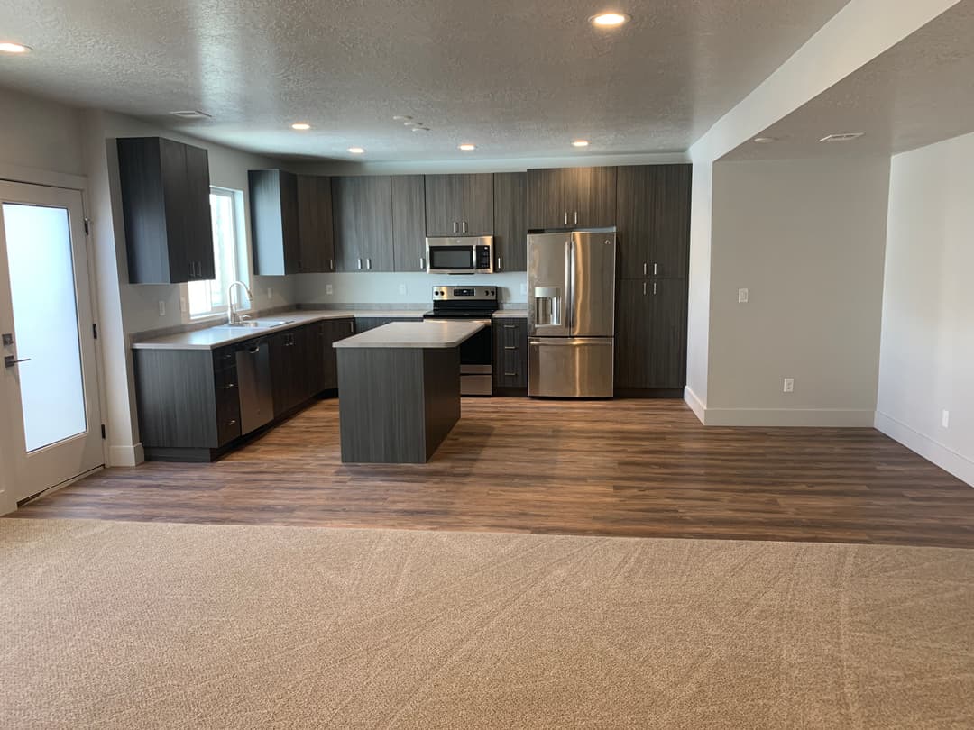 Modern open-concept kitchen and living area with stainless steel appliances and hardwood floors.