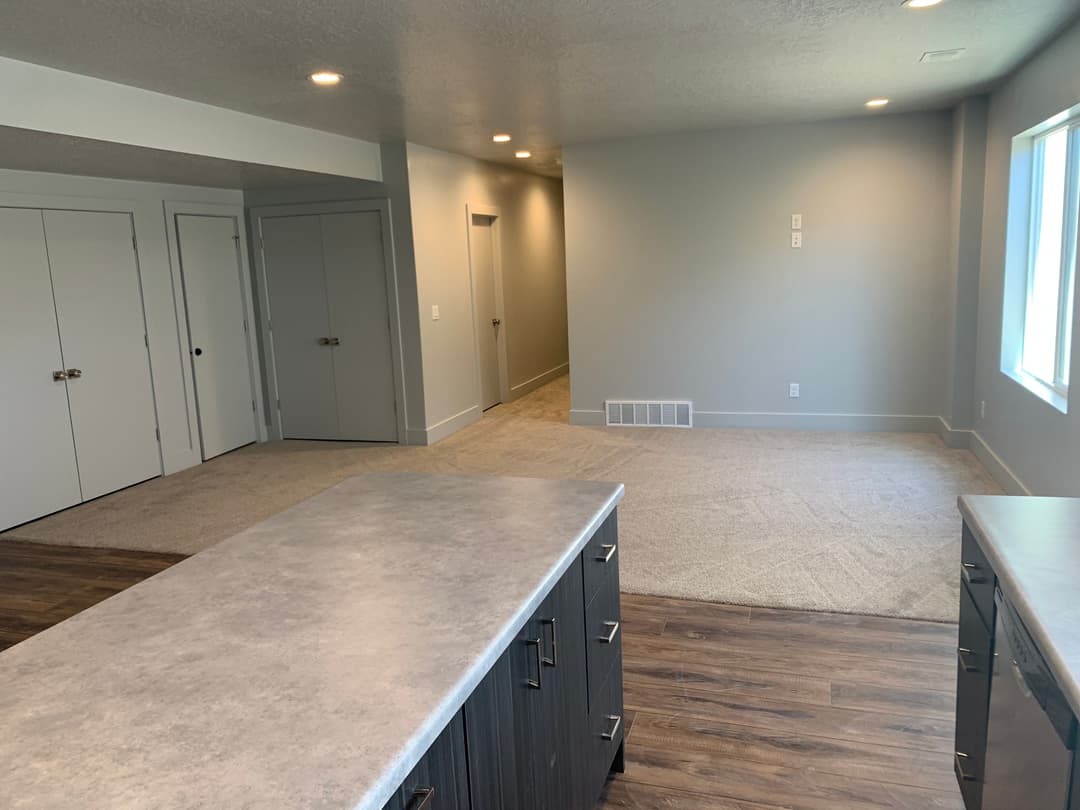 Modern living room with gray walls, carpet flooring, and a view of a bright window.