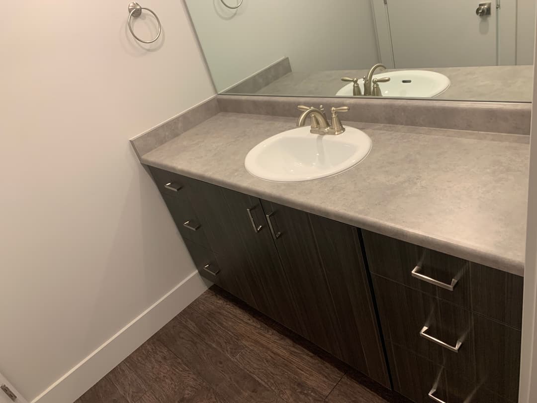 Modern bathroom vanity with a white sink, dark wood cabinets, and a stylish faucet.