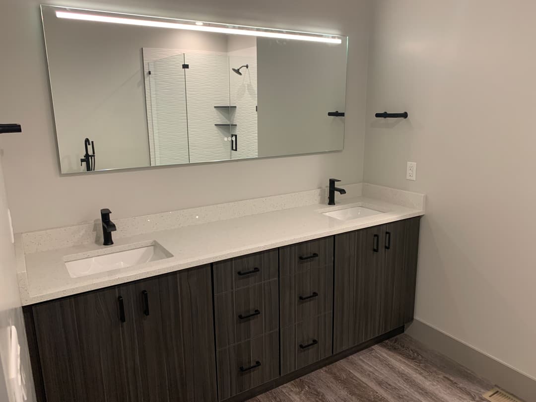 Modern bathroom with dual sinks, sleek cabinetry, large mirror, and stylish fixtures.