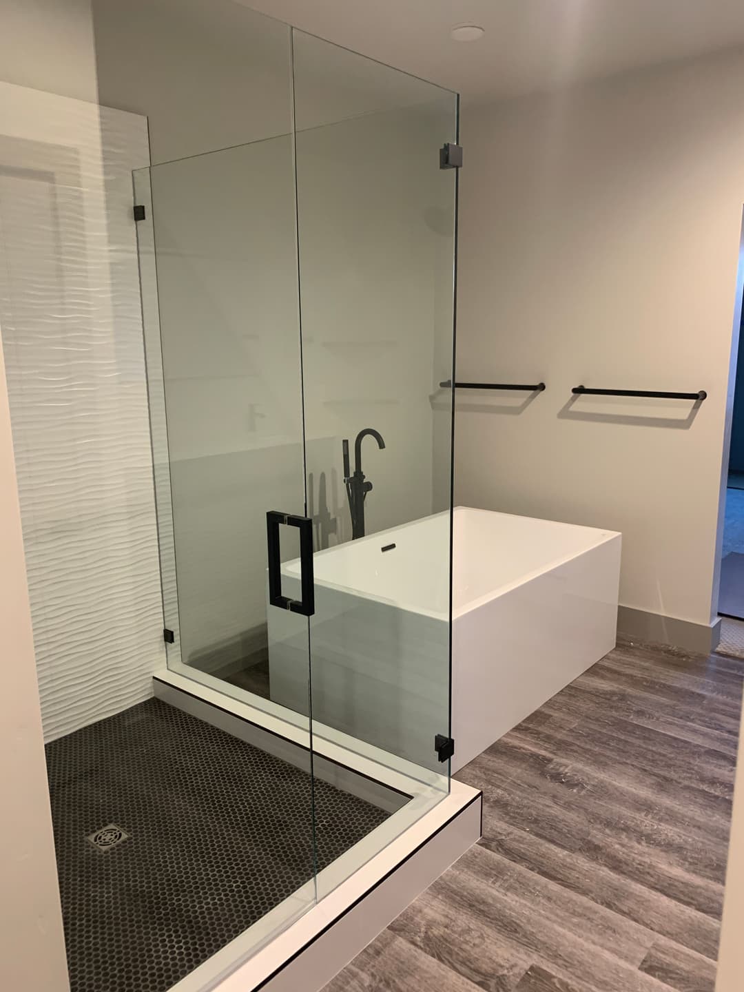 Modern bathroom design featuring a glass shower, freestanding tub, and stylish flooring.